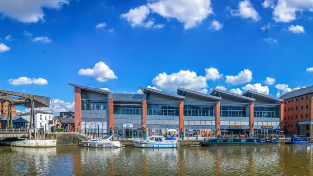 Exterior view of a waterfront store with boats parked in front