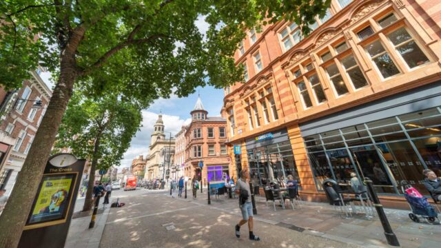 A town centre street with various shoppes and people walking around