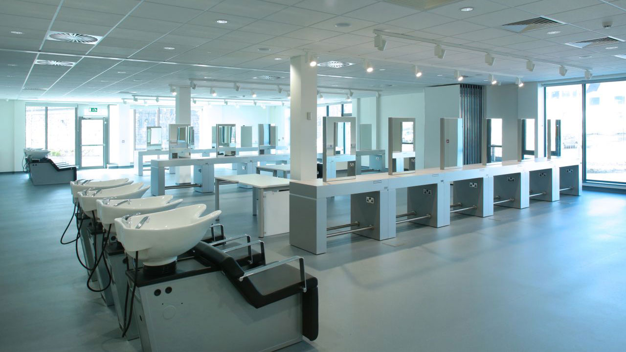 A modern salon training space featuring multiple hair washing stations and styling mirrors.