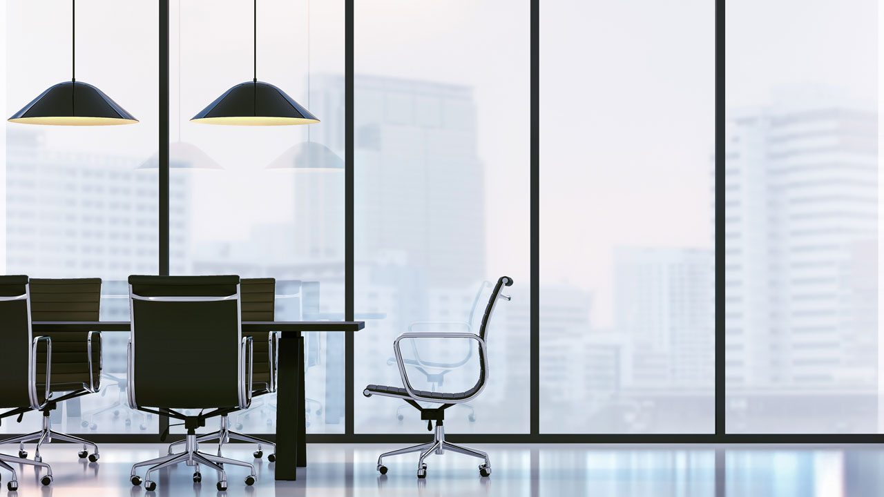 Modern office conference room with a glass wall, featuring a large table, black chairs, and city skyline in the background.