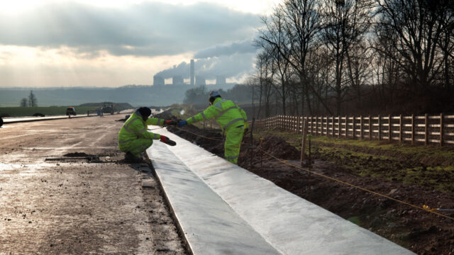 Two workers in hi-visibility clothing working on the construction of a highway