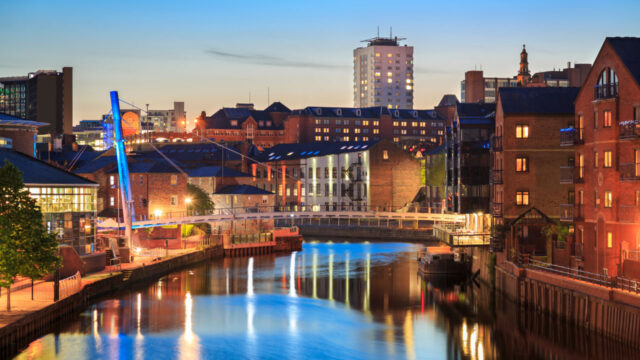 Waterway through city at night, lights and blue sky reflecting