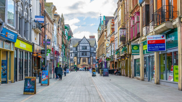 Pedestrian traffic on street lined with two-story businesses with colorful signage