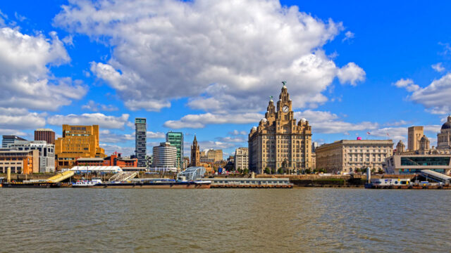 City skyline with clocktower on water against cloudy blue sky