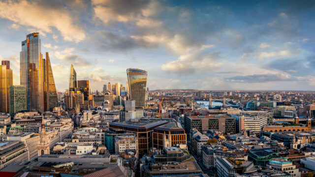 Aerial view of city with tall skyscrapers against bright sky with clouds