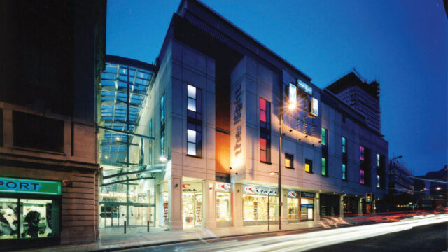 Retail buildings in an urban setting, lit up by a street lamp at night time