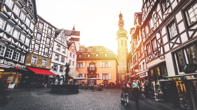 Cobblestone courtyard with fountain surrounded by white buildings featuring X-shaped patterns under the windows