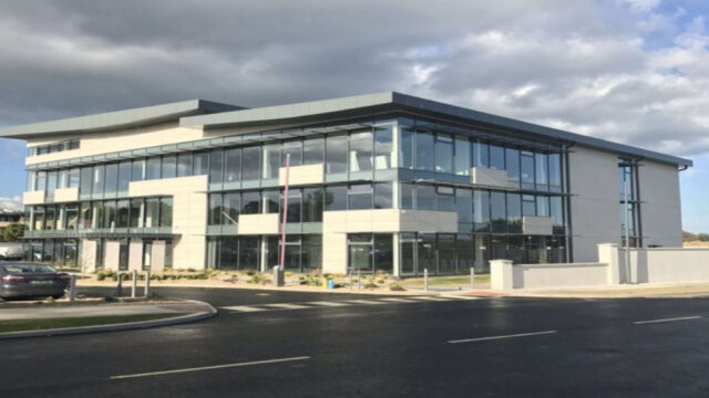 Modern three-story building with numerous windows against cloudy sky