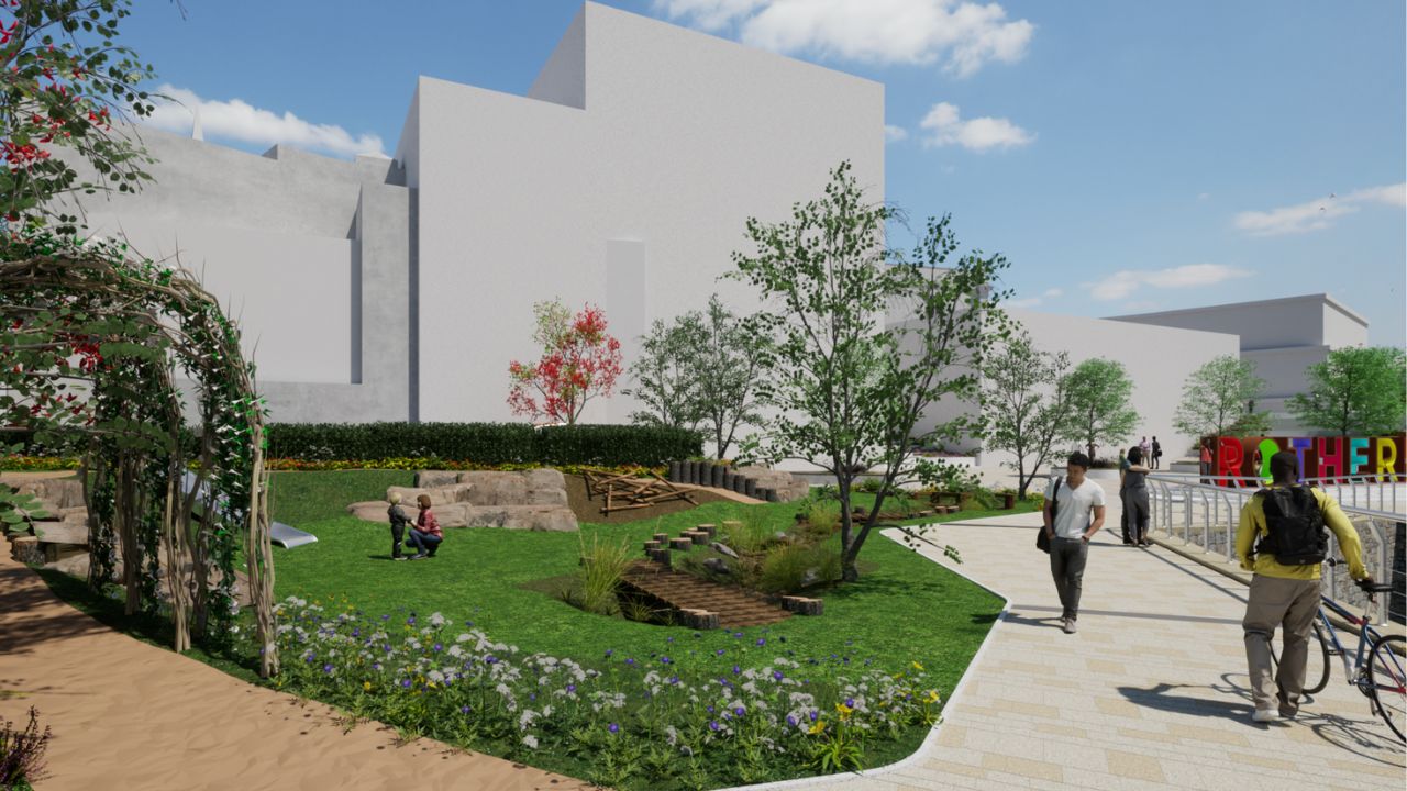 A digital rendering of an urban park with green grass, trees, flowers, a wooden play structure, and people walking and interacting. A colourful "Rotherham" sign is visible in the background near white modern buildings under a blue sky.