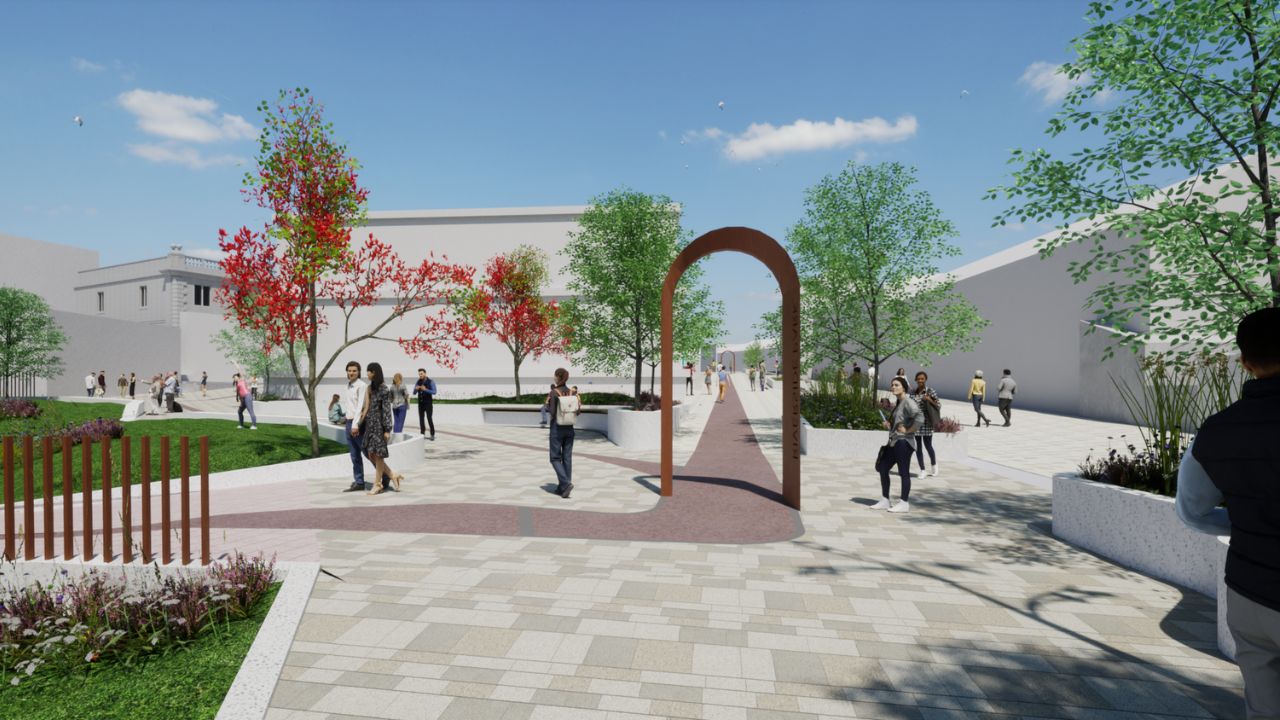 A digital rendering of an urban park walkway with paved paths, green lawns, trees with green and red leaves, a rust-coloured metal archway, and people walking and socialising under a clear blue sky.